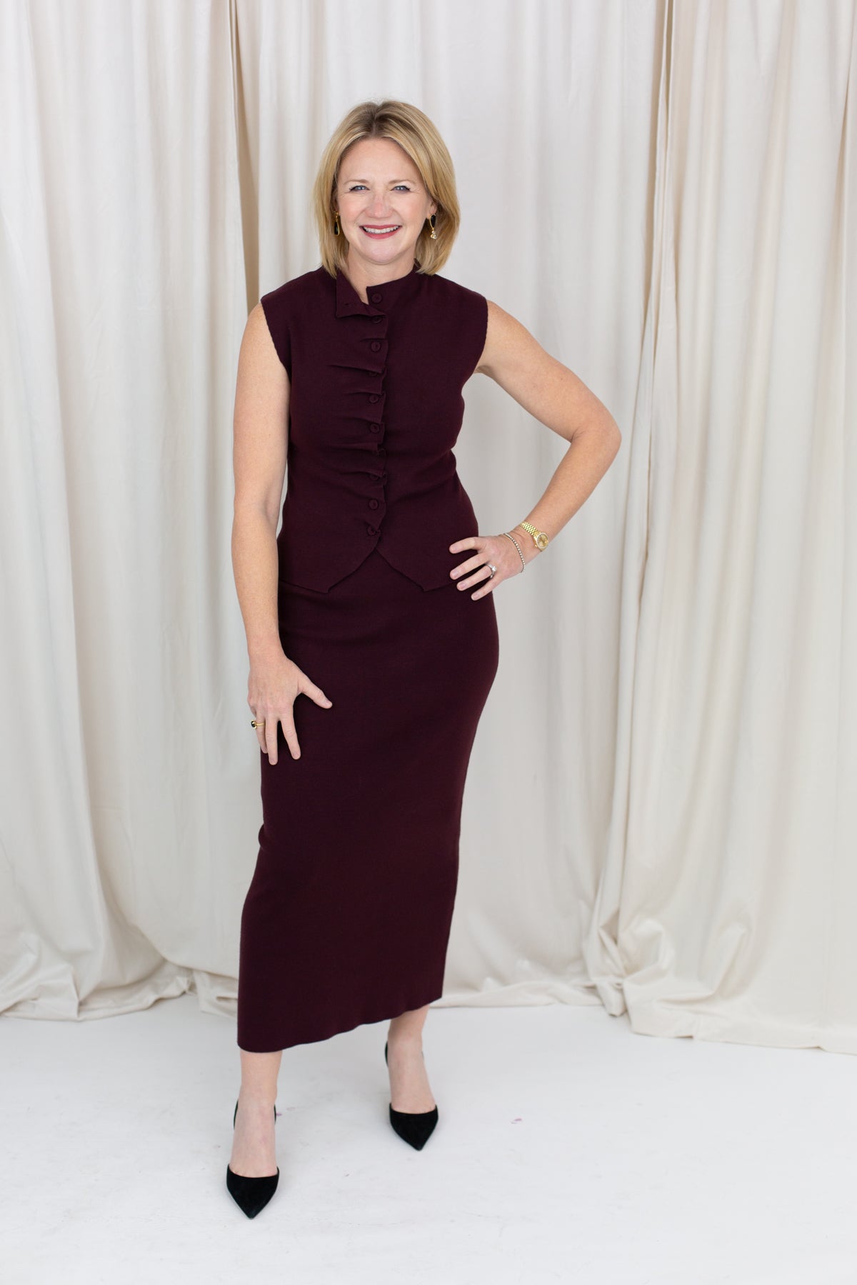 Coordinated burgundy pleated top and skirt set styled for a polished seasonal look