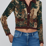 A cropped long-sleeve button-front cardigan with a dark green and beige toile-style print, worn by a model with blue jeans against a light gray studio background.