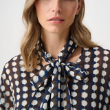 Model wearing a long-sleeve chiffon blouse with a geometric print and tie-neck detail in a relaxed, feminine silhouette.