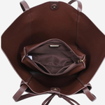 A brown leather tote bag shown from a top-down view, displaying its interior with a main compartment, a zippered pocket, and a drawstring closure on a light gray background.