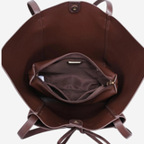 A brown leather tote bag shown from a top-down view, displaying its interior with a main compartment, a zippered pocket, and a drawstring closure on a light gray background.