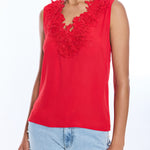 Red sleeveless top with floral details worn by a person on a white background