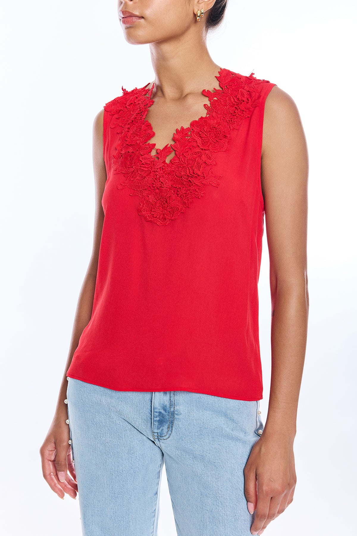 Red sleeveless top with floral details worn by a person on a white background