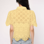 Person wearing a yellow lace top and blue jeans on a white background