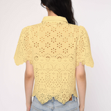 Person wearing a yellow lace top and blue jeans on a white background