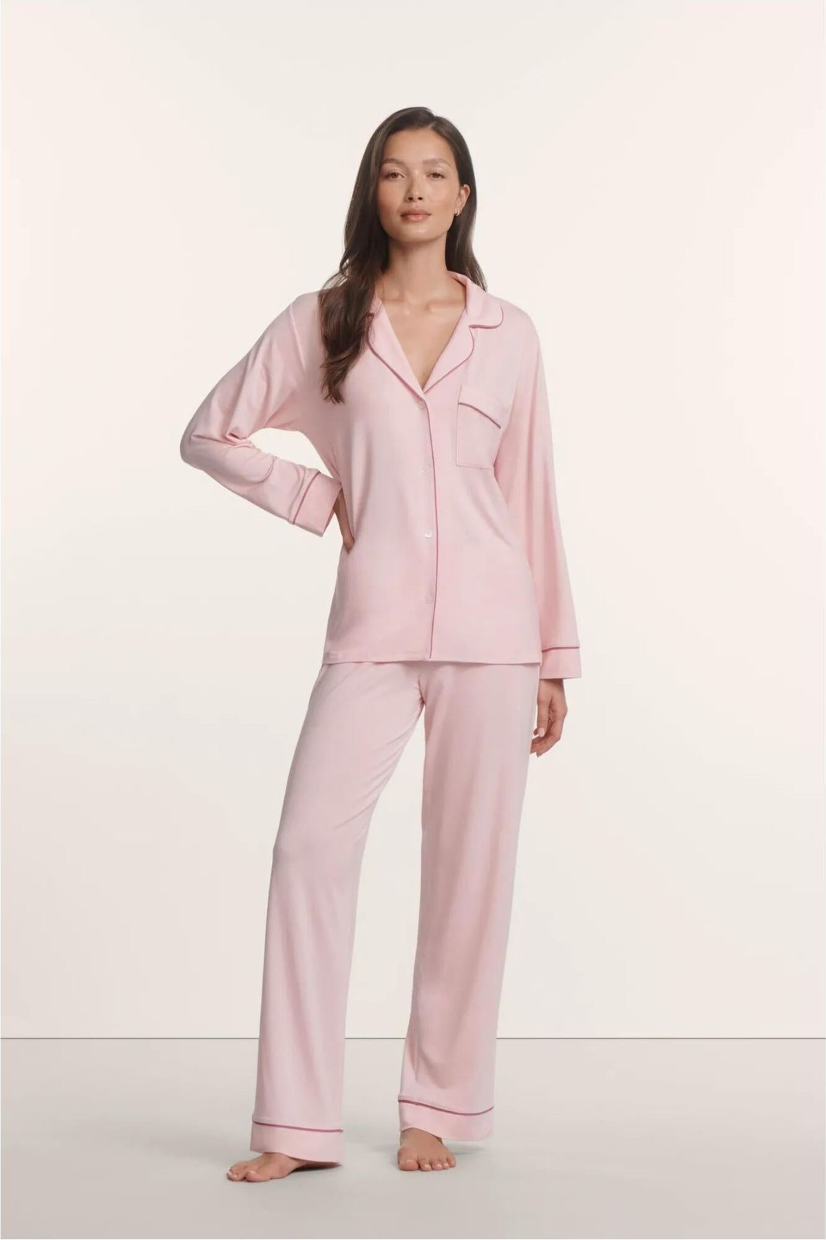 Woman wearing a pink pajama set against a white background
