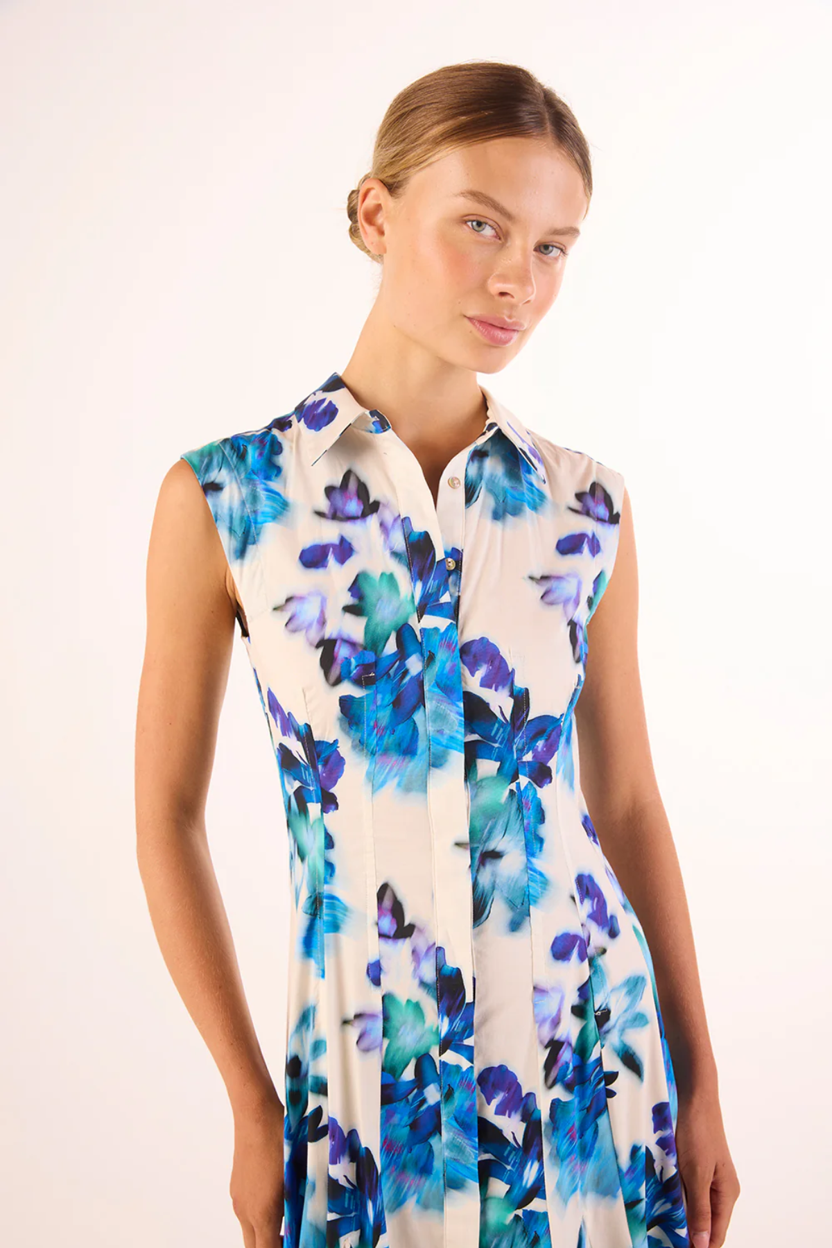 Woman wearing a sleeveless dress with blue floral pattern on a white background