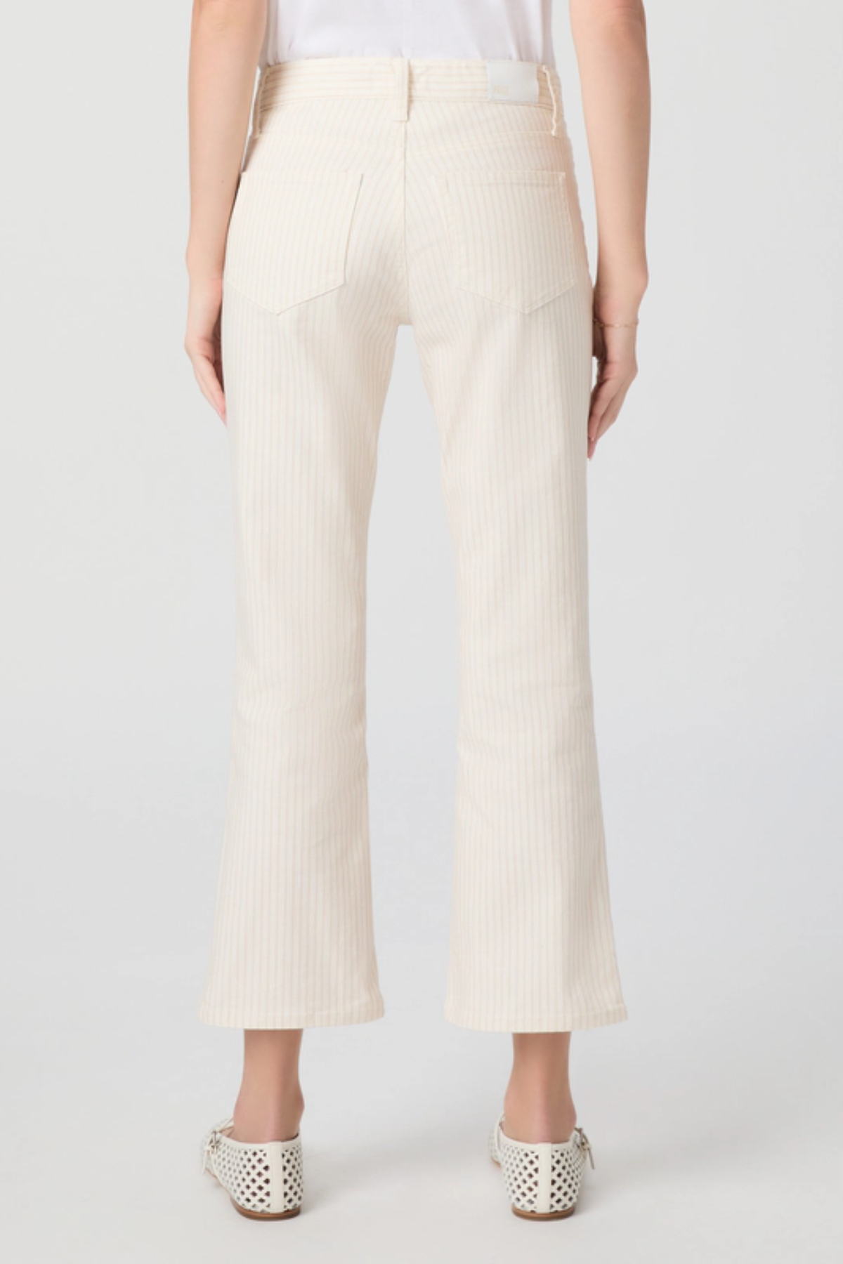 Person wearing white ribbed pants on a plain background