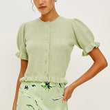 Woman wearing a light green cardigan and floral skirt on a white background