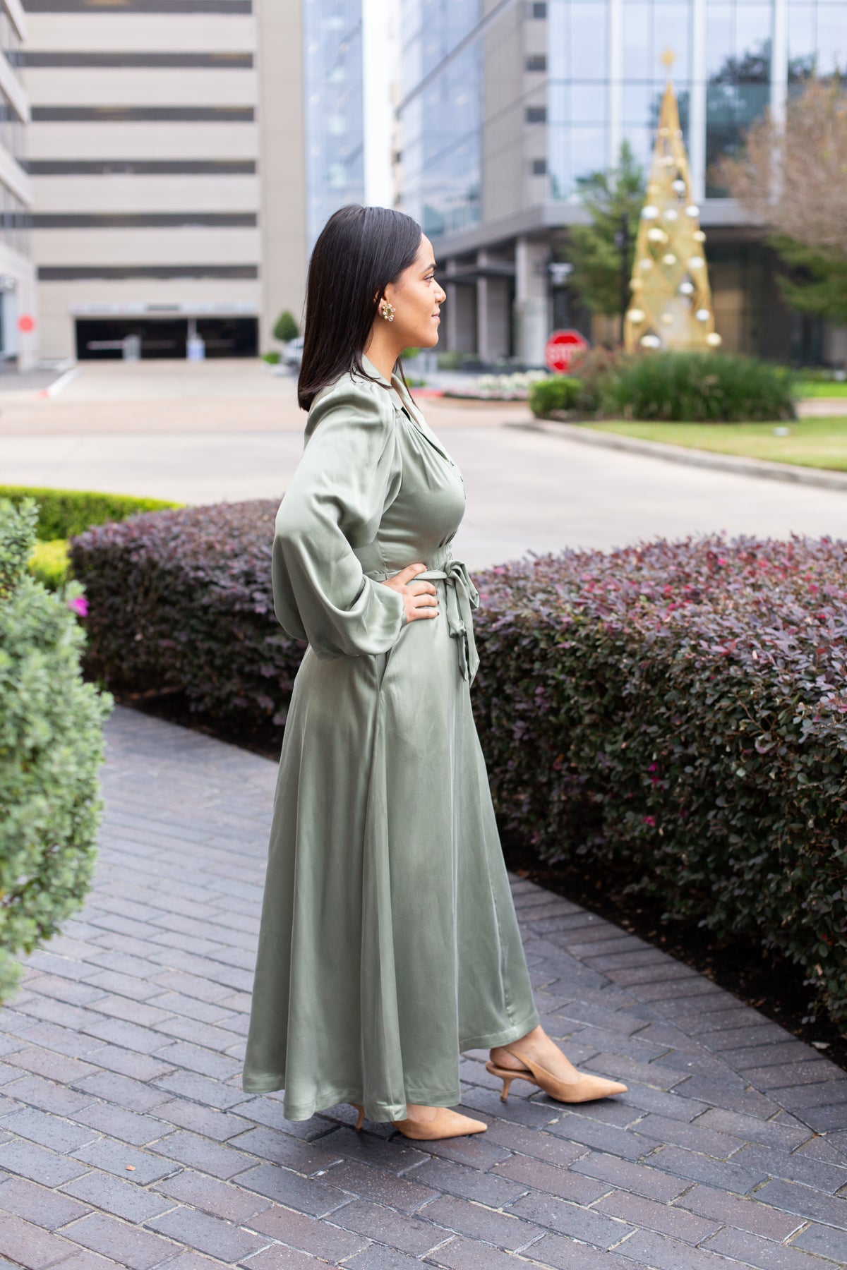Woman wearing a neutral midi dress with soft pleating and a relaxed, polished silhouette