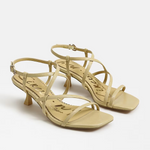 Pair of yellow high-heeled sandals on a white background