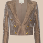 A cropped double-breasted blazer in a metallic bronze fabric with gold buttons, shown flat against a solid beige background. The brand label 'L'AGENCE' is visible at the collar.