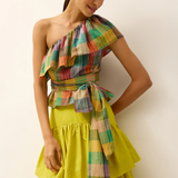 Woman wearing a colorful one-shoulder top and yellow skirt against a white background