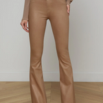 Person wearing brown flared pants and a matching top on a wooden floor with a white wall background.