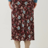 A person shown from the back wearing a dark floral midi skirt with a blue sweater and beige heeled boots against a plain light background.