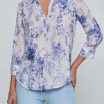 Person wearing a blue floral shirt and light blue jeans on a gray background