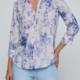 Person wearing a blue floral shirt and light blue jeans on a gray background