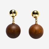 A pair of drop earrings featuring round dark brown wooden beads suspended from shiny gold-tone studs, shown against a plain light gray background.