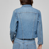 Person wearing a blue denim jacket and pants on a gray background