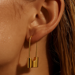 Close-up of a gold earring worn on an ear with a blurred background