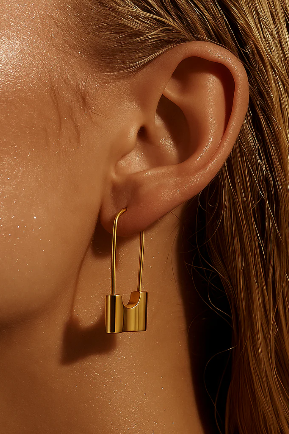 Close-up of a gold earring worn on an ear with a blurred background
