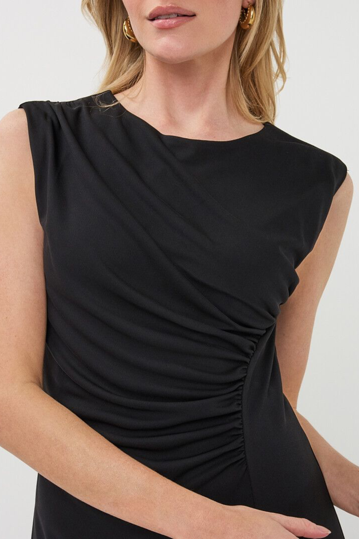 Black sleeveless dress worn by a model on a white background