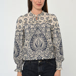 Woman wearing a patterned long sleeve blouse with a gathered neckline in neutral tones