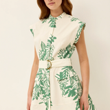 Woman wearing a white dress with green leaf pattern on a plain background