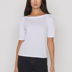 Woman wearing a white t-shirt and black pants against a plain background