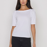 Woman wearing a white t-shirt and black pants against a plain background