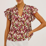 Woman wearing a floral blouse with ruffled sleeves on a plain background