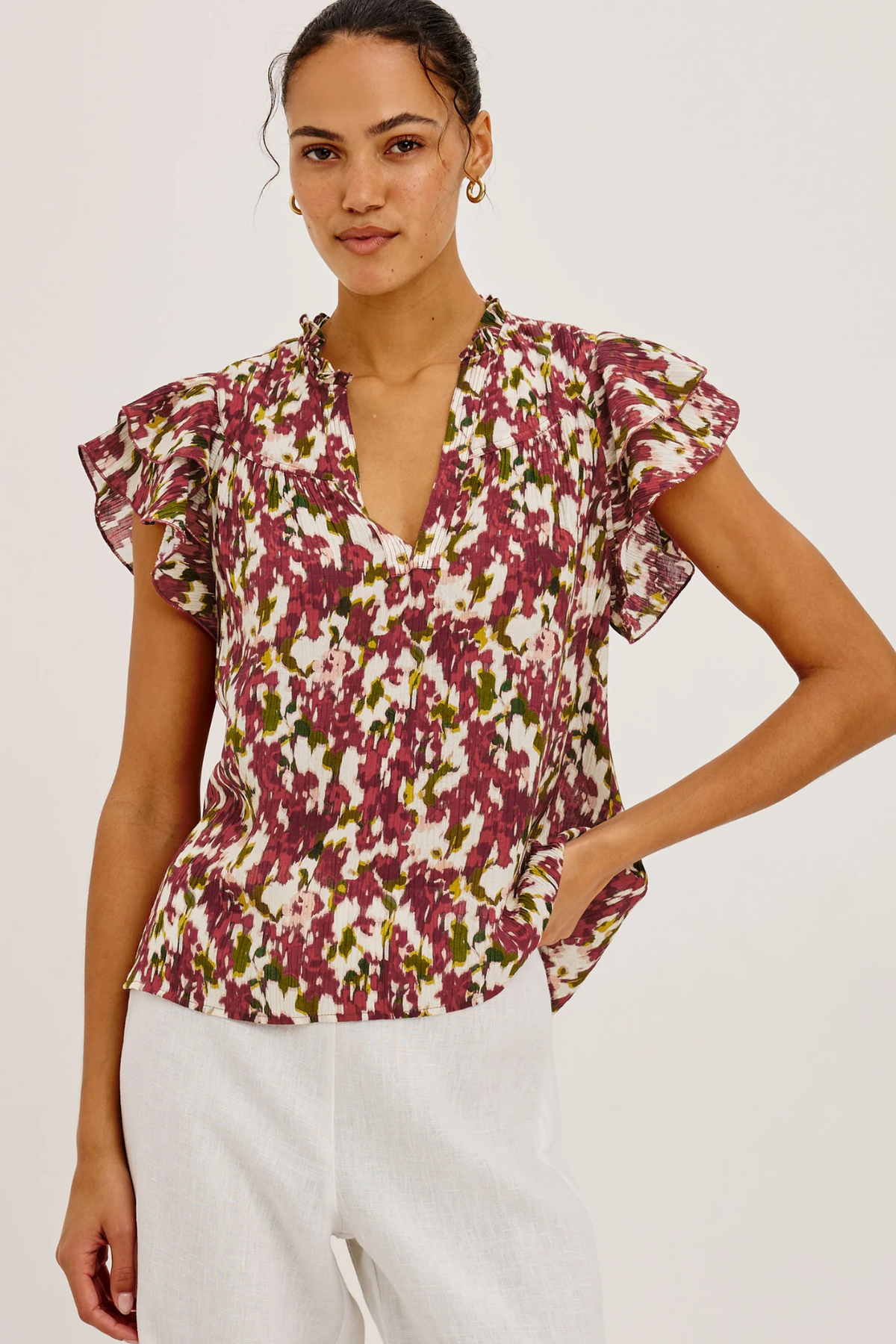 Woman wearing a floral blouse with ruffled sleeves on a plain background