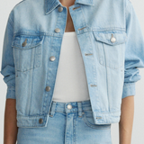 Light blue denim jacket worn by a person on a plain background