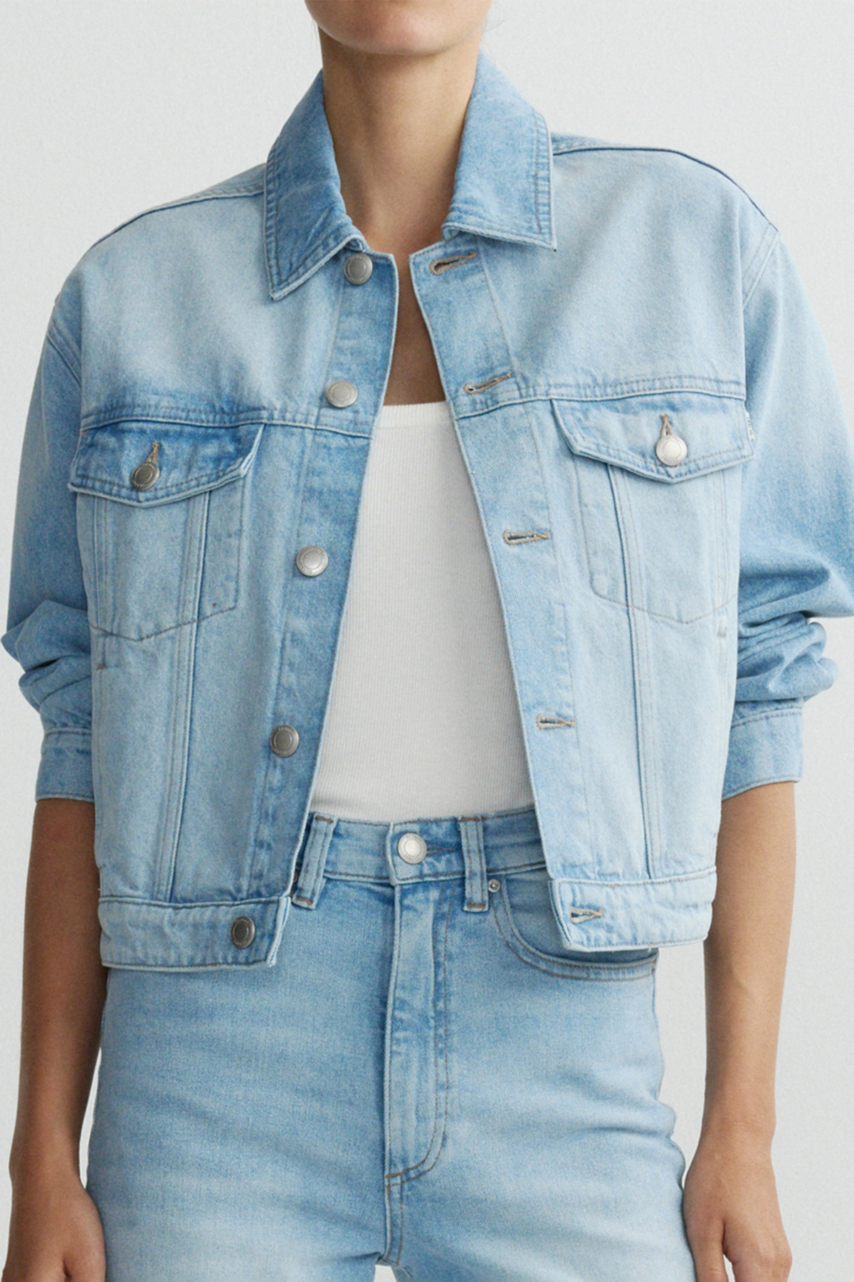 Light blue denim jacket worn by a person on a plain background