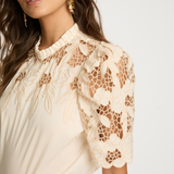 Woman wearing a beige lace blouse against a white background