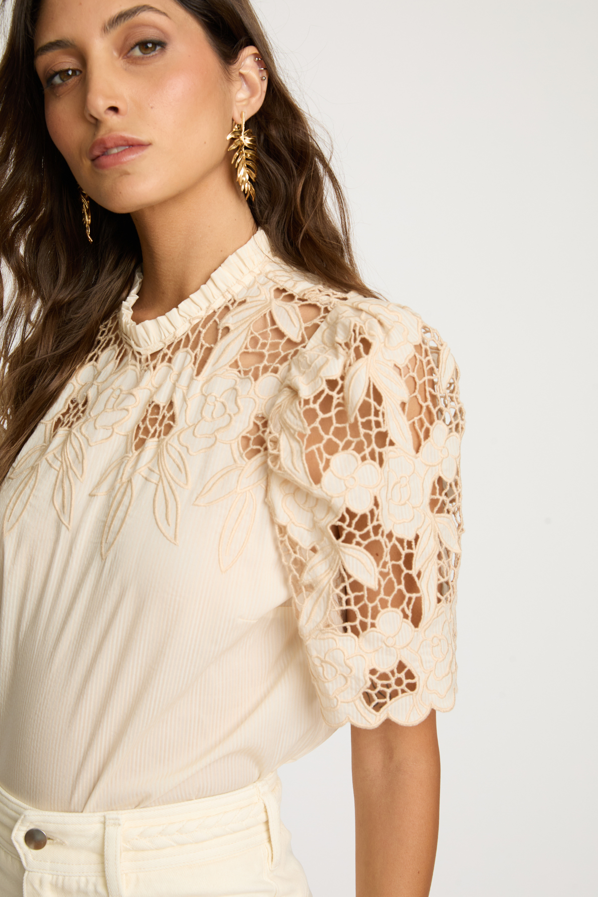 Woman wearing a beige lace blouse against a white background