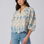 Woman wearing a floral blouse and jeans on a plain background