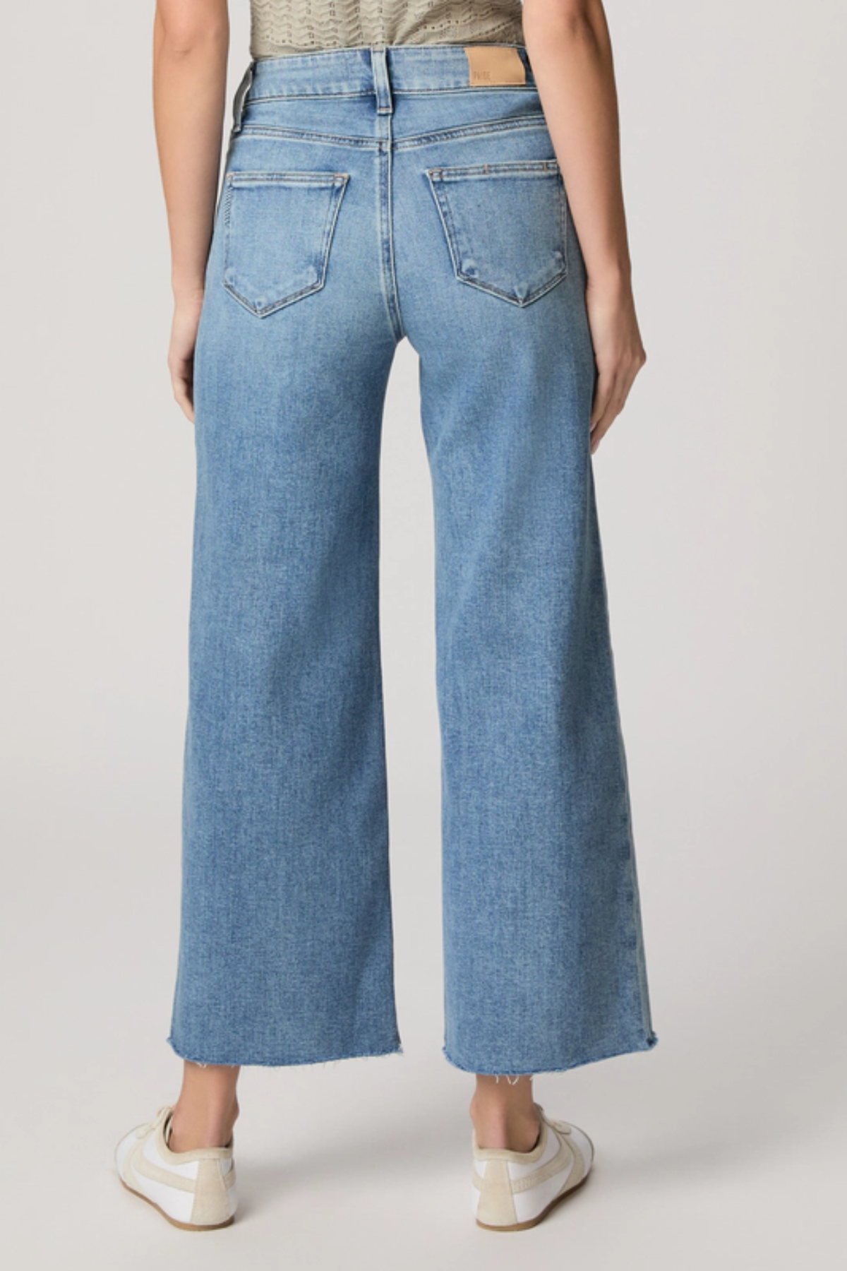 Person wearing light blue wide-leg jeans on a plain background