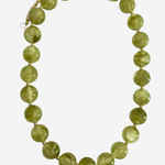A beaded necklace made of faceted olive green glass beads separated by small gold spacers, with a gold chain extender and clasp, shown on a light gray background.