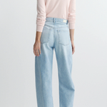 Person wearing light blue jeans and a pink sweater on a white background