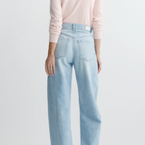 Person wearing light blue jeans and a pink sweater on a white background