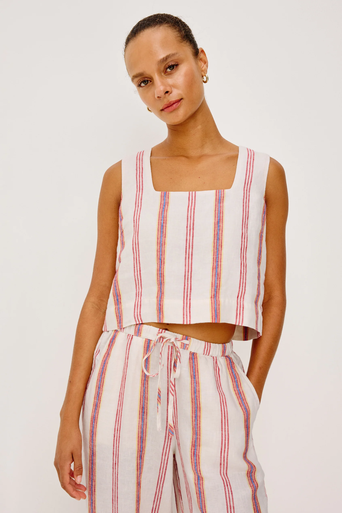 Woman wearing a striped sleeveless top and pants on a white background