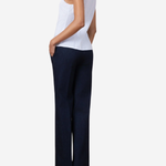 A woman shown from the back wearing a white ribbed sleeveless top and dark navy wide-leg trousers, standing against a light gray studio background.