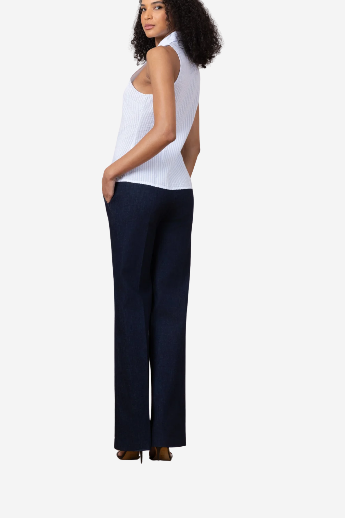 A woman shown from the back wearing a white ribbed sleeveless top and dark navy wide-leg trousers, standing against a light gray studio background.