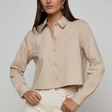 Woman wearing a beige ribbed blouse with a plain background