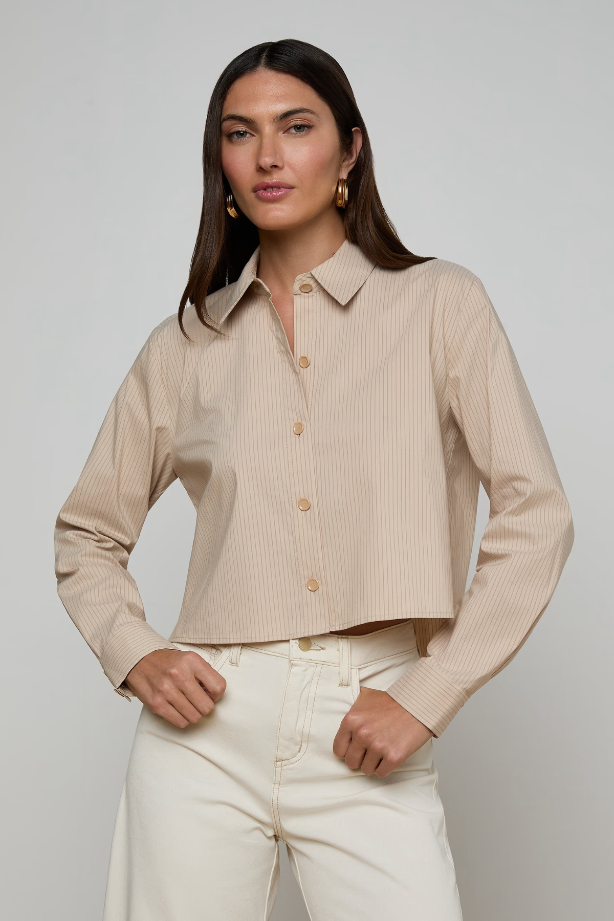 Woman wearing a beige ribbed blouse with a plain background