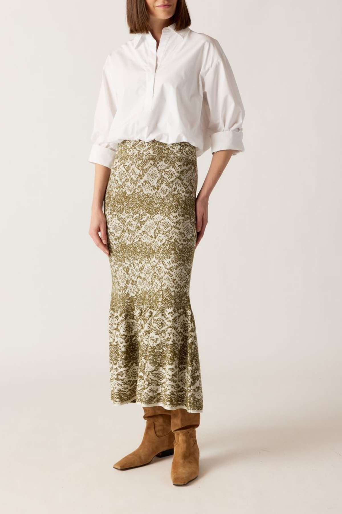 Woman wearing a white blouse and patterned skirt with brown boots on a white background