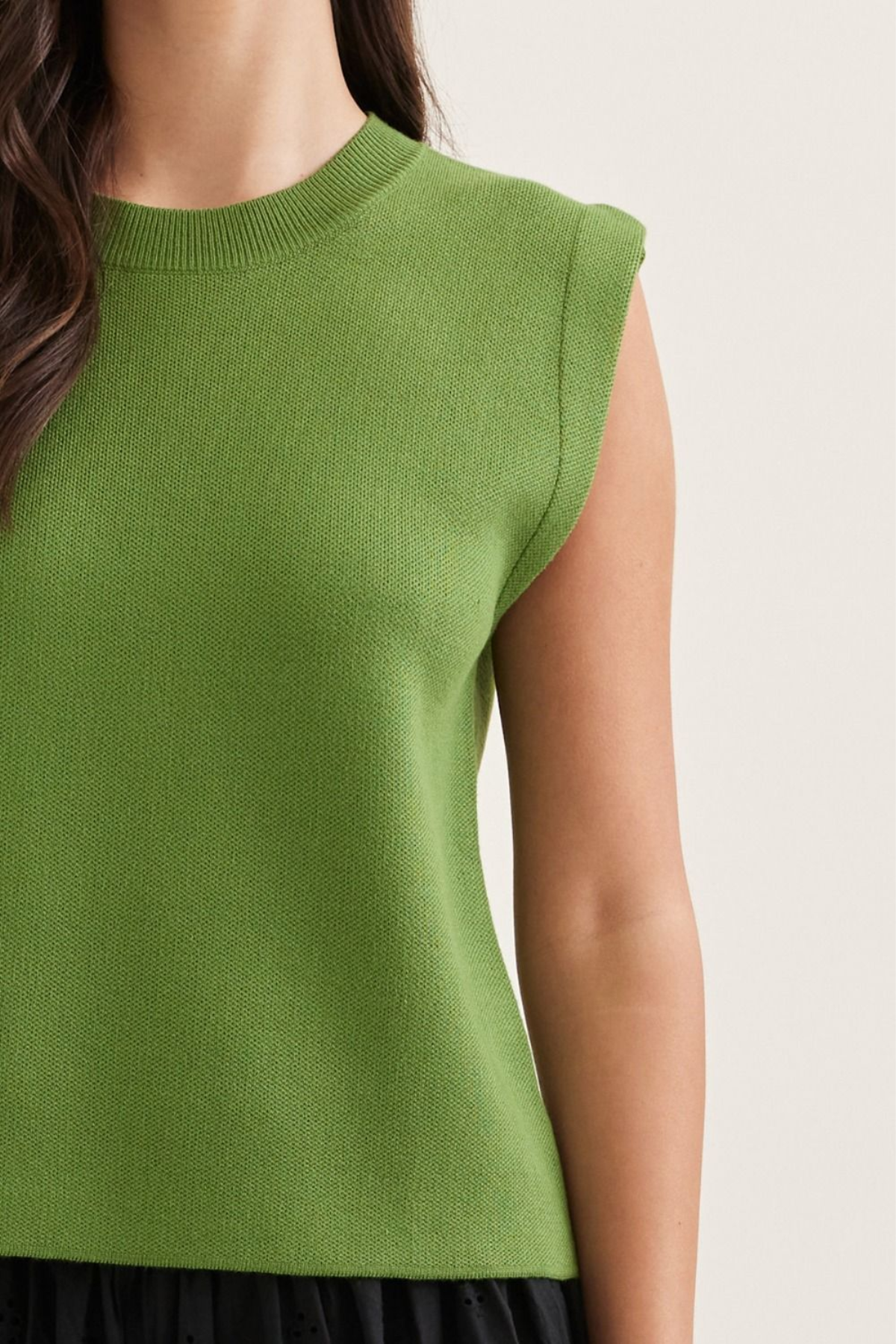 Green sleeveless top worn by a person on a plain background