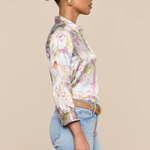 Woman wearing a floral blouse and jeans against a beige background