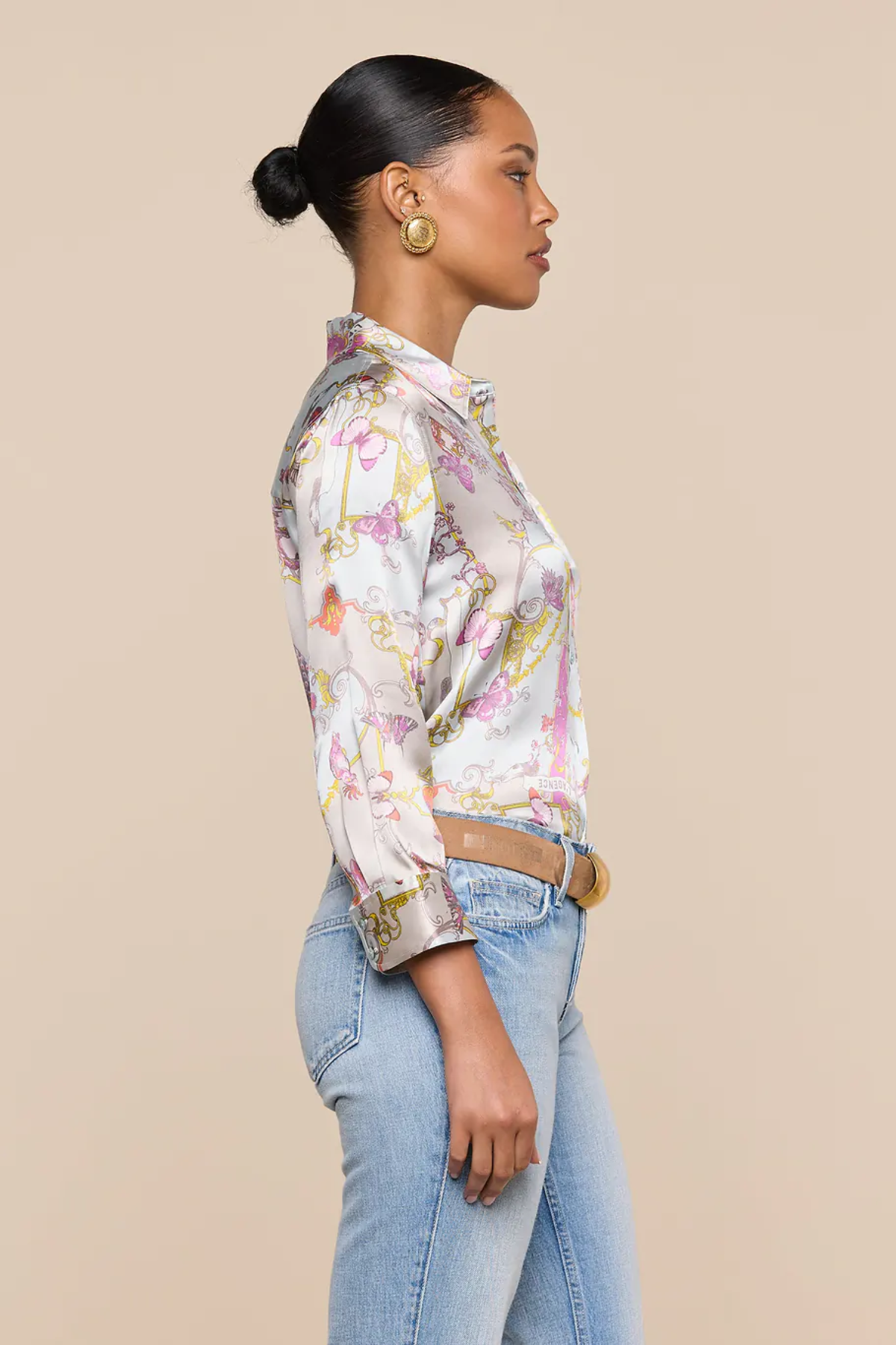 Woman wearing a floral blouse and jeans against a beige background